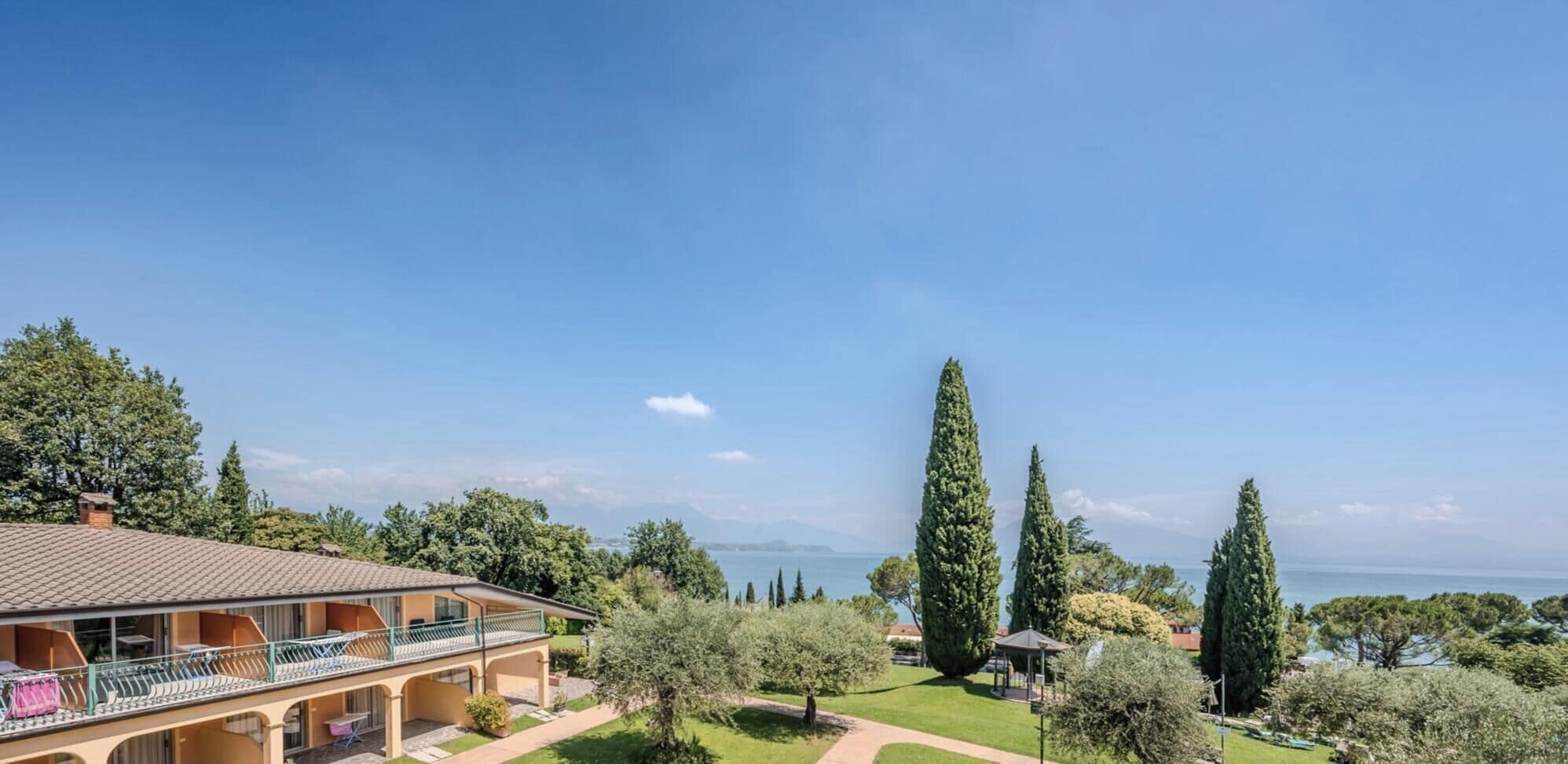 A coastal property with a large house, a garden, and a view of the sea.