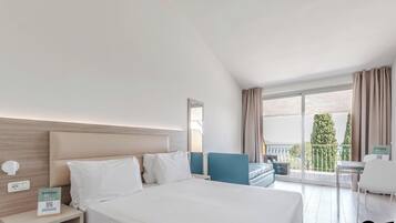 Habitación de hotel con una cama grande, un escritorio con silla, un balcón con vistas y un cartel con el nombre del hotel.