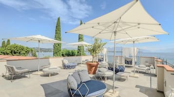 Eine Dachterrasse mit Sitzgelegenheiten, Sonnenschirmen und Blick aufs Meer.