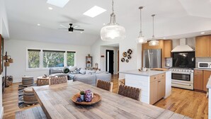 A modern kitchen with a central island, stainless steel appliances, and a dining area with a wooden table. - Spacious and Modern North Fork Home Close to Multiple Wineries, Perfect for... (Cutchogue)