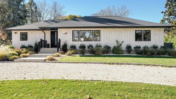 A single-story building with a flat roof, a front entrance with steps, and a gravel driveway.
