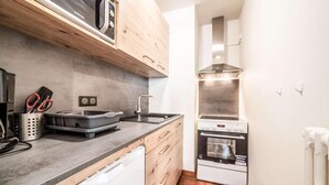 Una cocina compacta con microondas, horno y lavamanos.