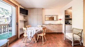 Una cocina compacta con comedor, un televisor montado en la pared y vistas al exterior.
