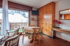A cozy dining area with a round table and chairs, wooden cabinets, and a view of a snowy landscape.