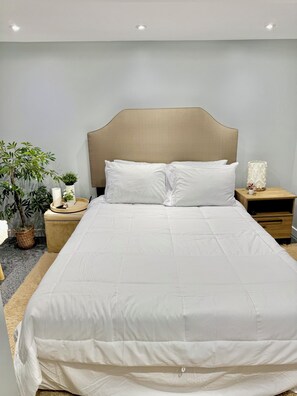 A neatly made bed with a wooden headboard, white bedding, and a bedside table with a lamp and a small plant. - Cozy/Modern Home in Minneapolis with 4 Bedrooms and 2 Bathrooms, Sleeps 8! (Minneapolis)