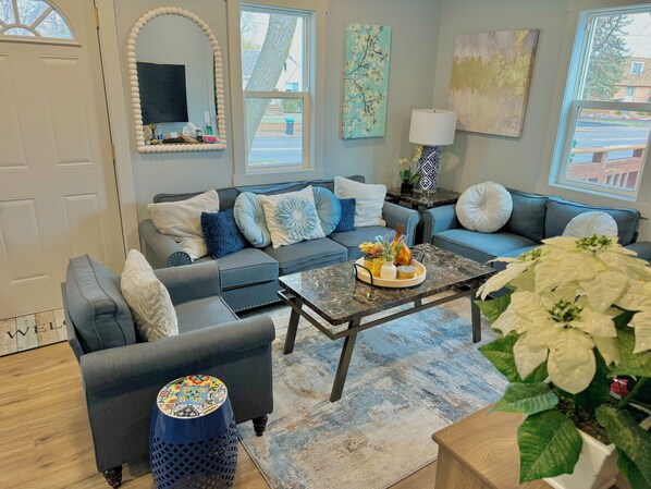 A modern living room with a grey sofa set, a coffee table with decorative items, a potted plant, and artwork on the walls. - Cozy/Modern Home in Minneapolis with 4 Bedrooms and 2 Bathrooms, Sleeps 8! (Minneapolis)