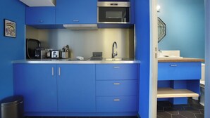 Une cuisine de taille réduite avec des meubles bleus, un four à micro-ondes en acier inoxydable et un évier.