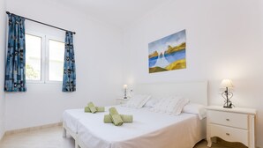 Un dormitorio con cama, mesitas de noche y un cuadro en la pared.