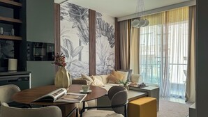 Una sala de estar moderna con comedor, un juego de sofá, una mesa de centro y un gran ventanal con cortinas.