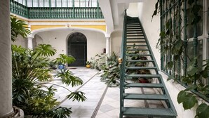 Una scala all'interno di un edificio, con pavimento piastrellato e circondata da piante in vaso.