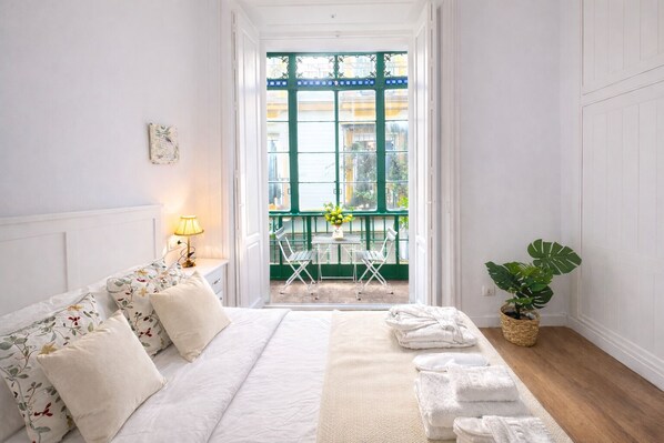 A bedroom with a bed, a nightstand, a lamp, a window with a view of the outside, and a potted plant. - Modern apartment with balcony and WiFi in Sevilla Centro (Sevilla)