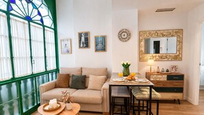Un soggiorno con un divano, un tavolo da pranzo con sedie, un tavolino con candele, uno specchio e opere d'arte alle pareti.