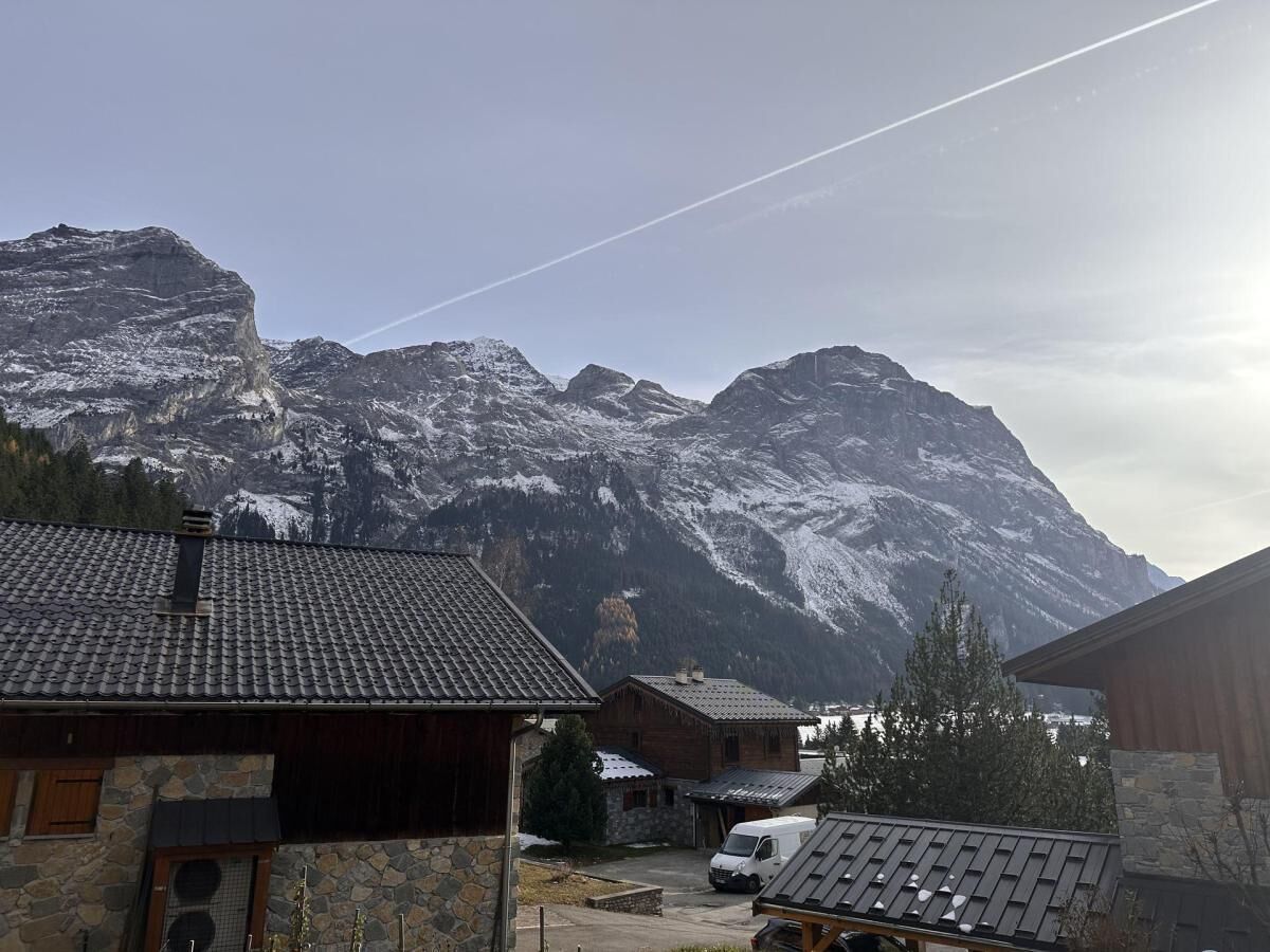 A mountain village with stone buildings and a view of snow-covered peaks.