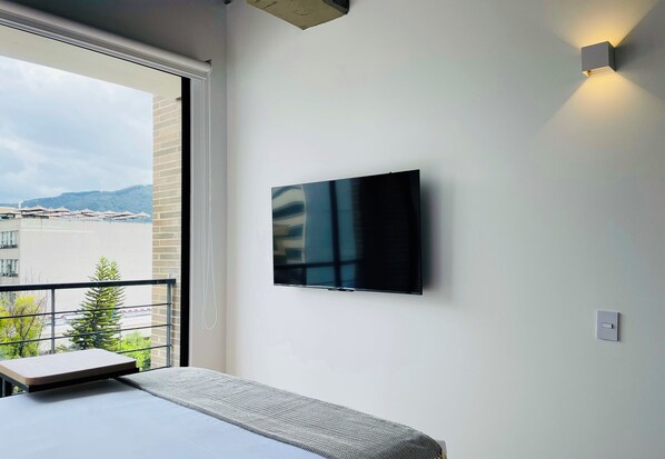 Enjoy city views and modern comforts in this stylish room with a large window, flat-screen TV, and comfortable bed.
