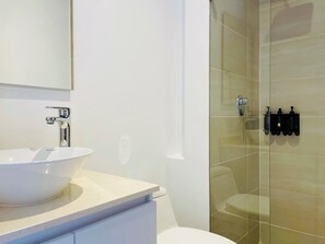 Bathroom features a large vessel sink, glass shower enclosure, and a minimalist design.