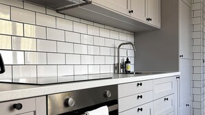 A modern kitchen with white cabinets, a stainless steel oven, and a black stovetop.