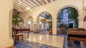 An interior courtyard with tiled flooring, wooden furniture, and potted plants. - Alta Gastelbondo (Cartagena de Indias)