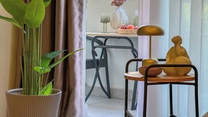 A room with a potted plant, a chair, a small table with a lamp, and a decorative item.
