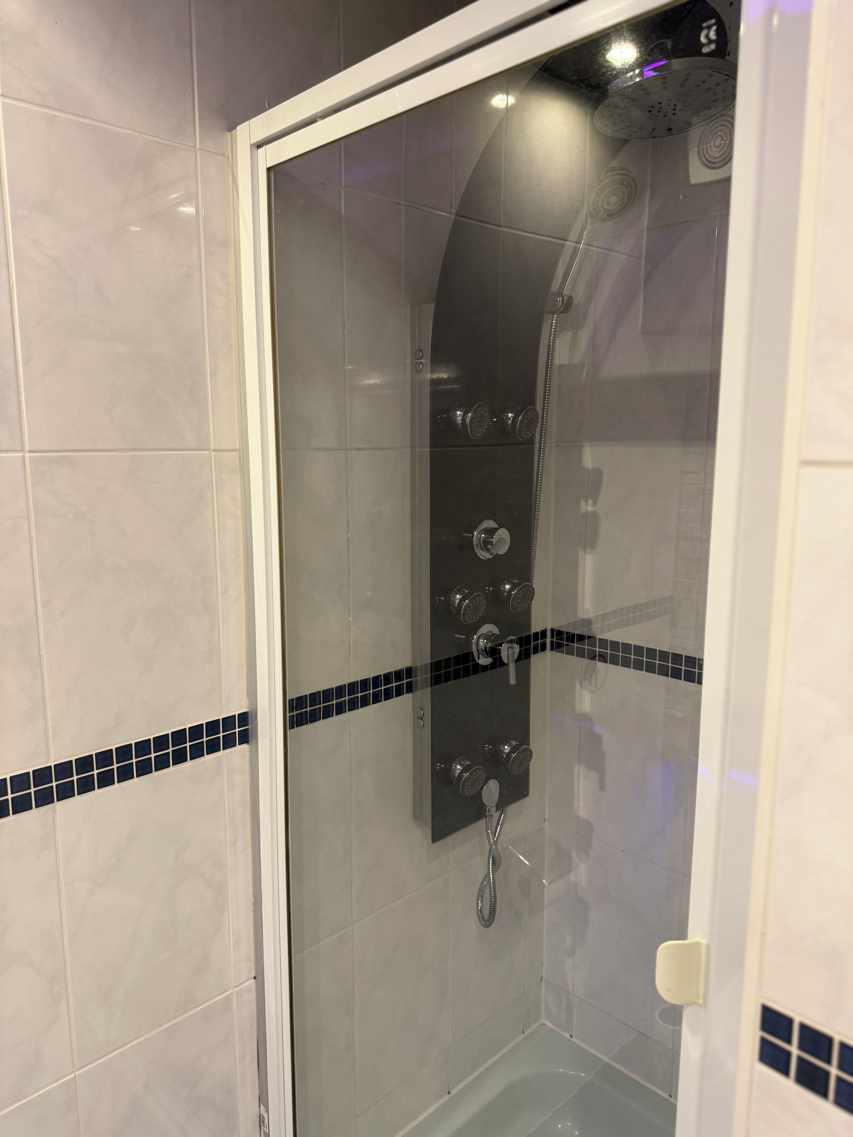 A glass-enclosed shower with multiple showerheads and a handheld showerhead.