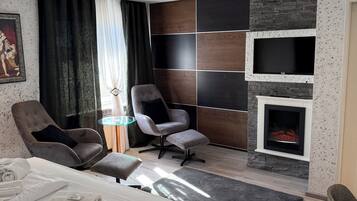 Habitació d'hotel moderna amb un llit, dues butaques, una llar de foc i una làmpada al sostre.