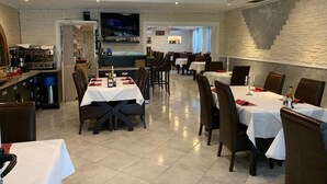 Een restaurant met verschillende tafels en stoelen, een keukenhoek en een stenen muur.