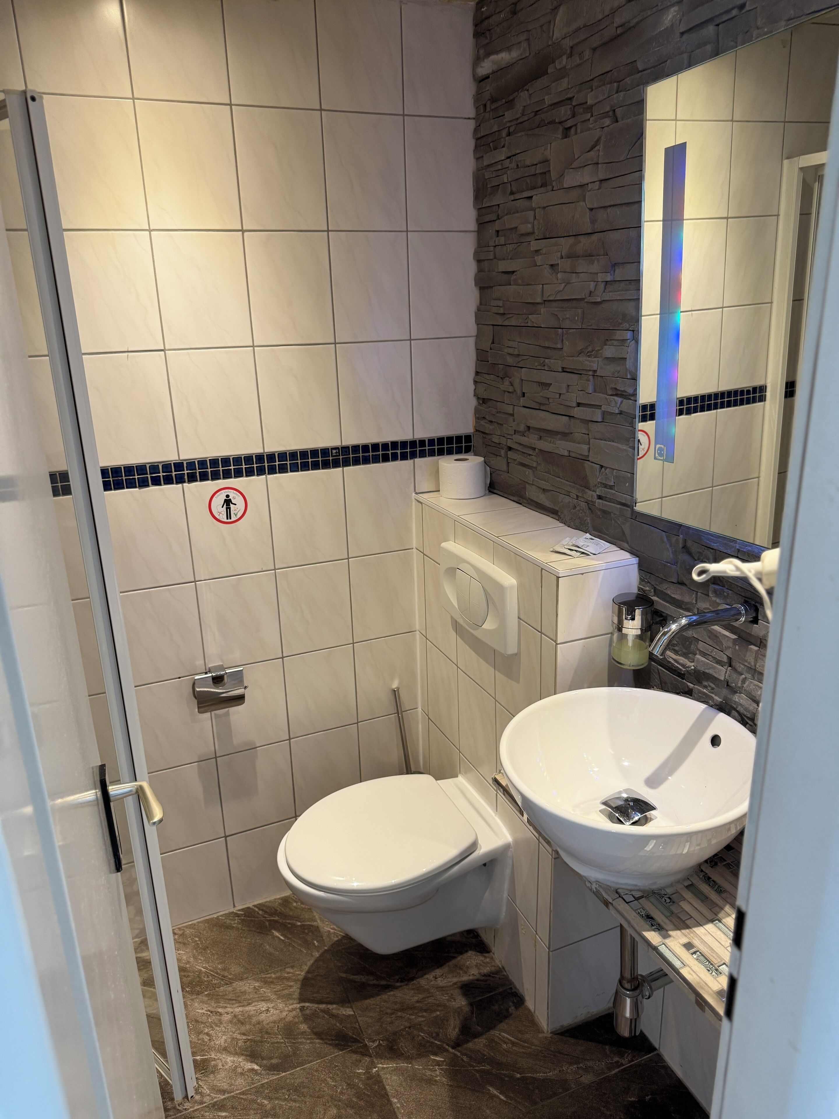 A modern bathroom with a toilet, sink, and mirror.