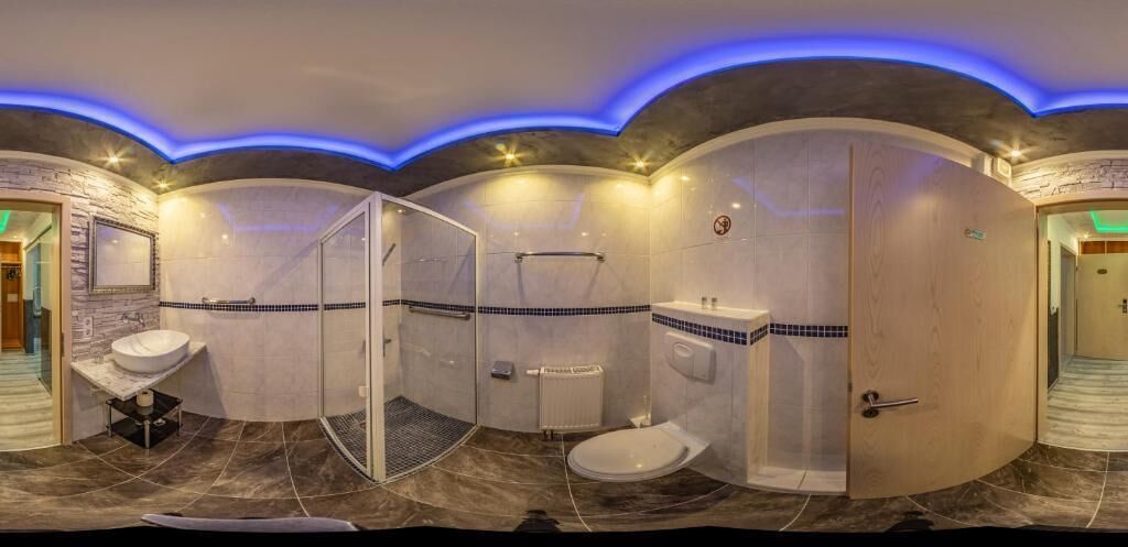 A modern bathroom with a curved design, a glass shower enclosure, a vanity with a mirror, and a toilet.