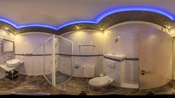 A modern bathroom with a curved design, a glass shower enclosure, a vanity with a mirror, and a toilet.