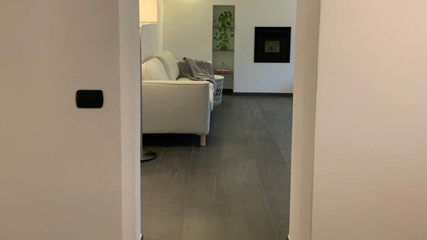 An interior view of a hallway leading to a living area with a sofa, lamp, and wall-mounted decor. - Spazio Perlasca apt1 - Cernobbio Como Lake (Cernobbio)