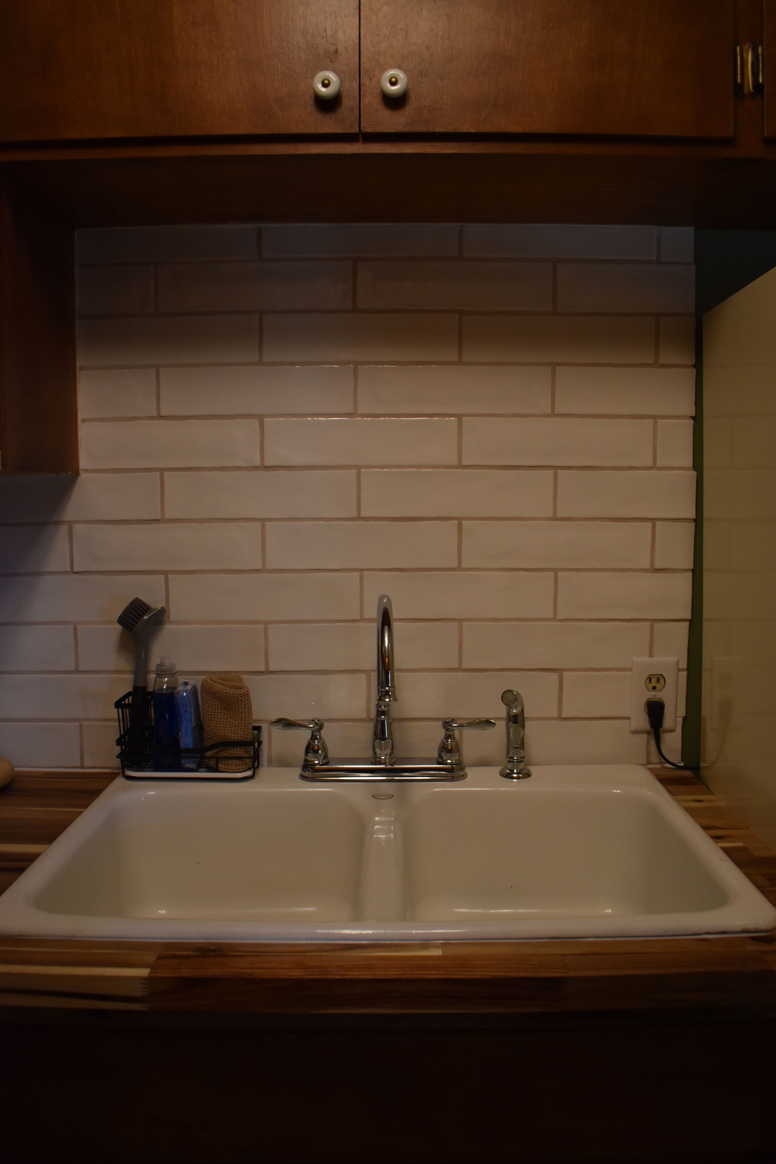 Cucina con lavello doppio, mobili in legno e schienale rivestito di piastrelle.
