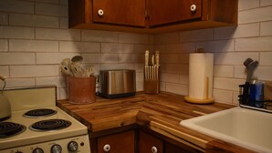 A kitchen with a wooden countertop, a stove, and cabinets. - Wildflower Suites North (Garfield)