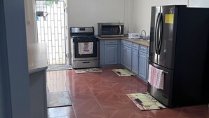A kitchen with a stove, microwave, refrigerator, and blue cabinets. - Charming 2-bedroom apartment with WiFi, AC in delightful Georgetown. (Georgetown)