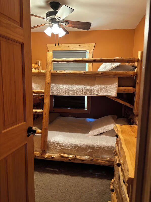 A bunk bed with a ceiling fan, wooden headboard, and a window with blinds. - Adirondack Retreat! Spacious 4-Bedroom Cabin in Old Forge, NY (Old Forge)