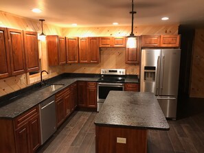 A modern kitchen with wooden cabinets, stainless steel appliances, and a granite countertop. - Adirondack Retreat! Spacious 4-Bedroom Cabin in Old Forge, NY (Old Forge)