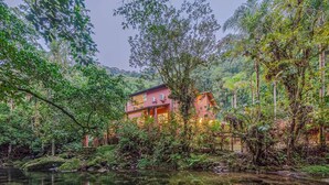 Una casa rodeada de un bosque frondoso y un estanque tranquilo.