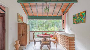 Un comedor con una mesa redonda, dos sillas, un aparador de madera y una ventana con vistas a zonas verdes.