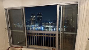 Un balcone con due sedie e vista sulla città illuminata di notte.