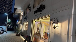 Una panetteria francese con vetrina in vetro e area salotto all'aperto.