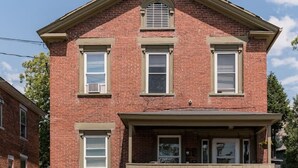 A two-story brick building with a central entrance, a small porch, and a garage.