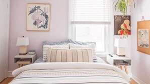 A bedroom with a bed, bedside tables, a window, and wall decorations.
