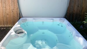 A hot tub with multiple jets, a control panel, and a drain.