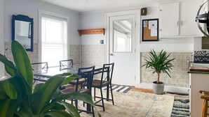 A modern kitchen with a dining table, chairs, a potted plant, and a tiled backsplash.