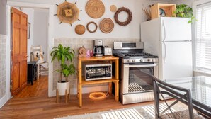 A compact kitchen with a stove, oven, microwave, and a small wooden table. - Bohemian Penthouse | 1min Walk Restaurants + Shops (Winooski)