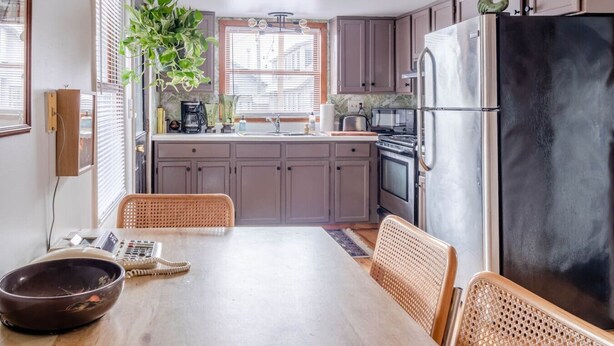 A kitchen with a dining table, chairs, a refrigerator, and a sink.