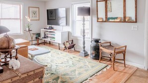 A living room with a TV, a lamp, a mirror, and a patterned rug.