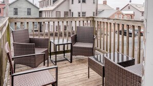 A wooden deck with wicker furniture and a view of residential buildings.