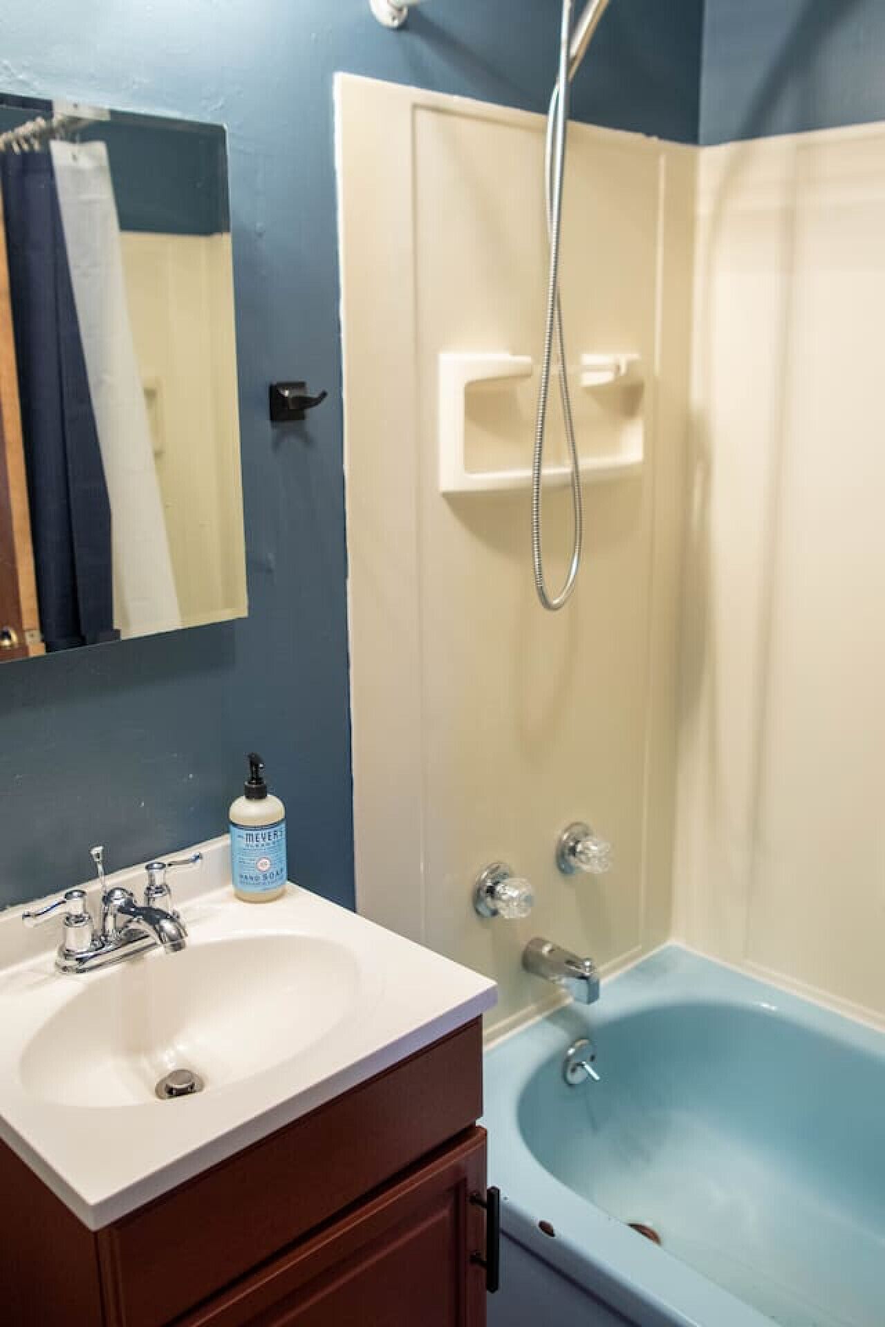 A bathroom with a white sink, a blue bathtub, and a shower enclosure.