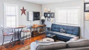 A cozy living room with a blue sofa, a wooden coffee table, a round dining table with chairs, and a star decoration on the wall. - Historic Farmhouse Apartment (Fairfield)