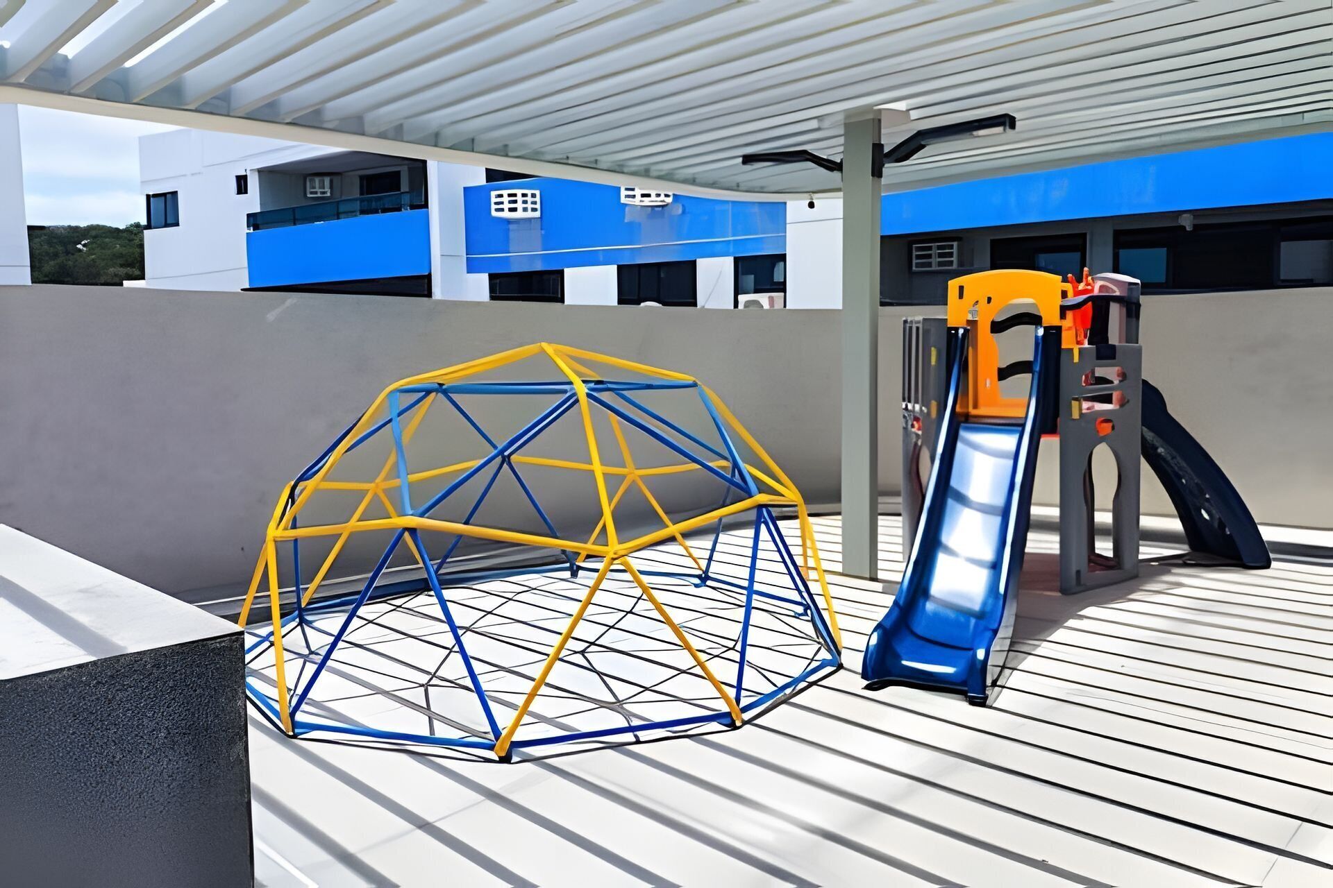 A playground with a slide and a climbing structure on a wooden deck.