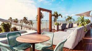 A rooftop terrace with a wooden table, green wicker chairs, and a white sofa. - Setai Yacht (João Pessoa)